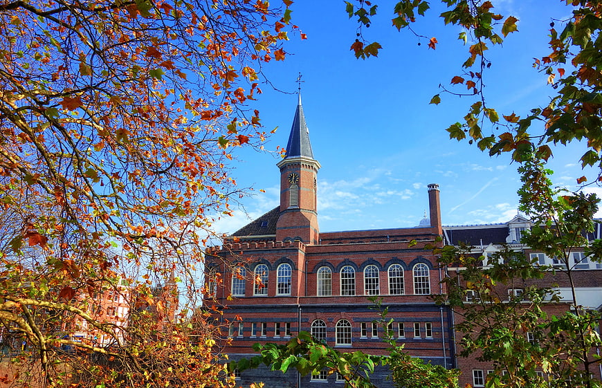 Historic Brick Building with Clock Tower Framed by Autumn Leaves