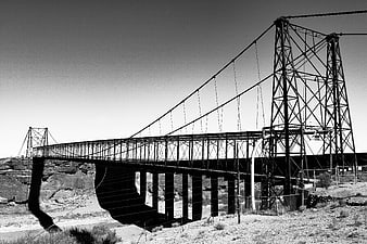 Black and white steel suspension bridge in desert landscape