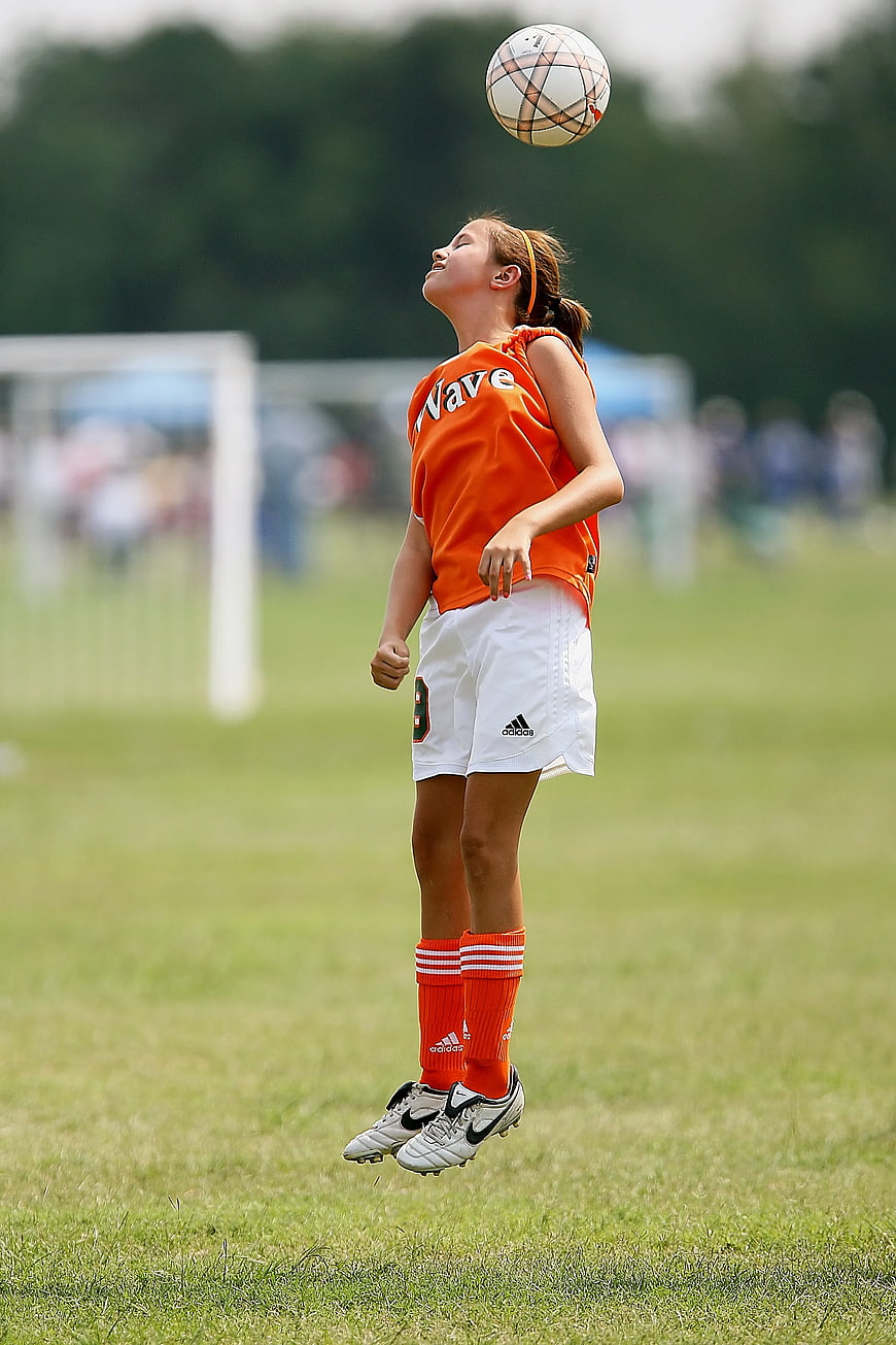 Young female soccer player heading a ball mid-air
