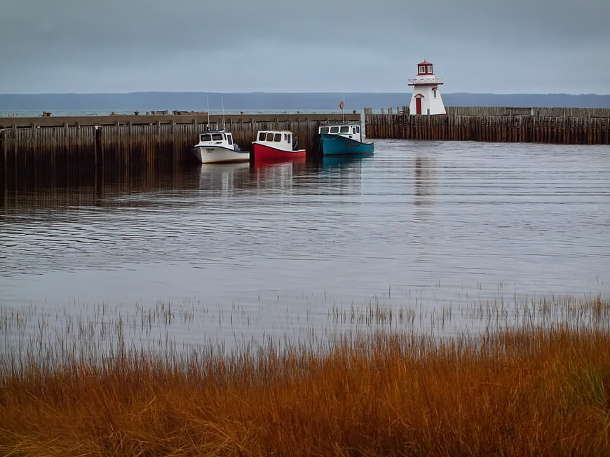 Colorful Fishing Boats Docked at Harbor with Lighthouse