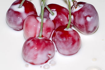 Fresh red cherries submerged in creamy white milk