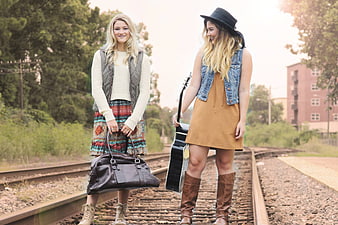 Two Young Women Standing on Train Tracks with Guitar and Bag