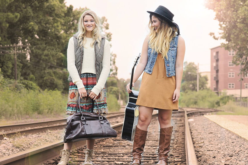 Two Young Women Standing on Train Tracks with Guitar and Bag
