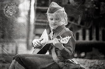 Girl in vintage military uniform playing balalaika