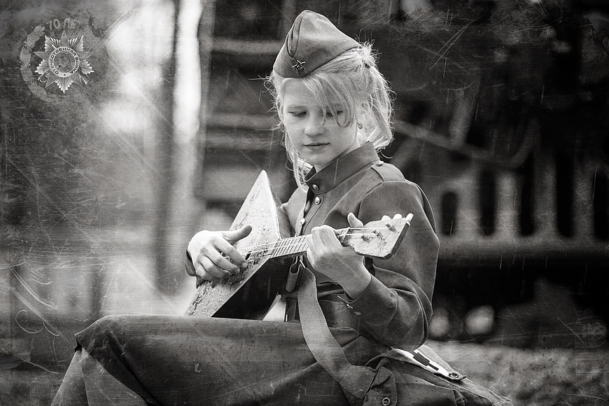 Girl in vintage military uniform playing balalaika