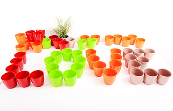 Colorful plastic cups arranged in a circle on white background