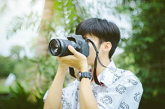 Young man taking photo with DSLR camera outdoors