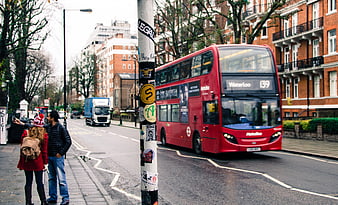 Red double-decker bus driving on London street