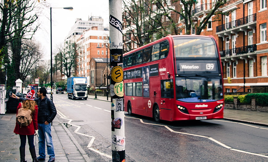 Red double-decker bus driving on London street