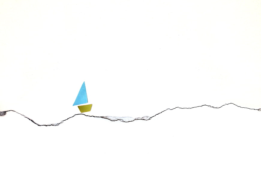 Minimalist paper sailboat on cracked white wall