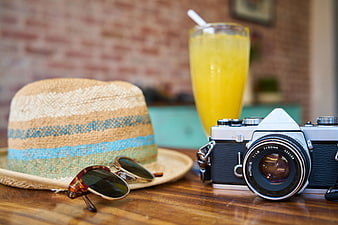 Vintage Camera, Straw Hat, and Sunglasses on Wooden Table