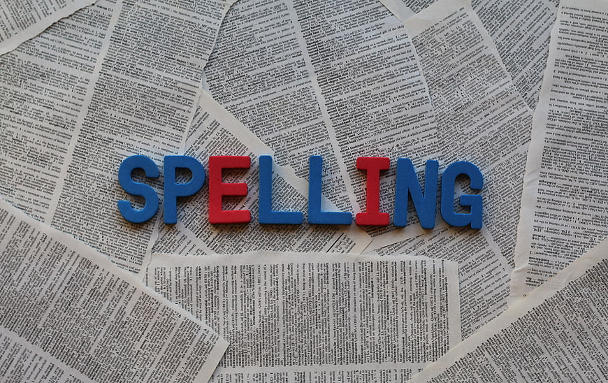 Spelling word made of colorful foam letters on newspaper background