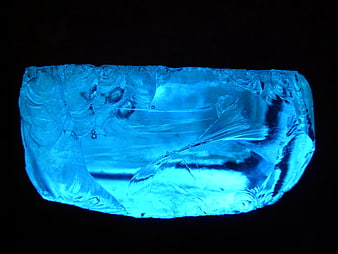 Glowing blue slag glass rock on black background