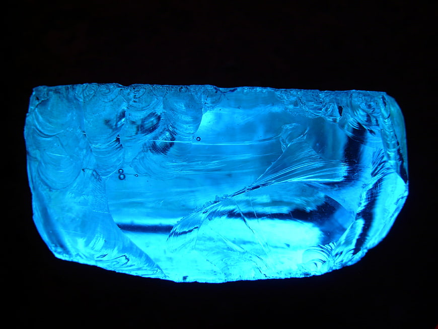 Glowing blue slag glass rock on black background