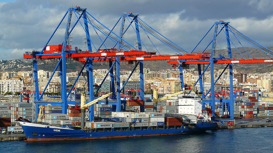 Container ship and cranes at busy seaport with city skyline