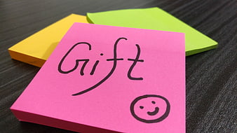 Pink sticky note with handwritten gift message and smiley face