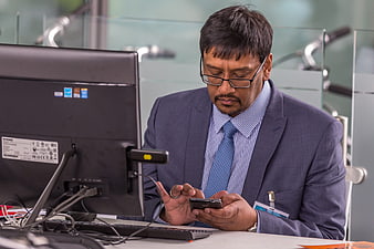 Businessman in Suit Using Smartphone at Office Desk