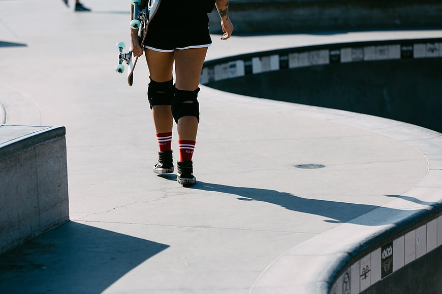 Skateboarder Walking in Concrete Skatepark