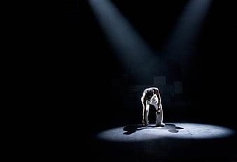 Lone dancer in spotlight on dark stage