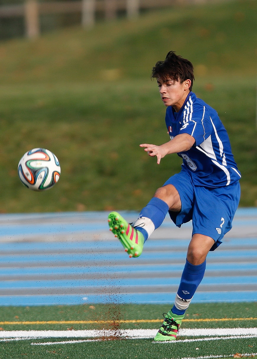 Young Soccer Player Kicking Ball on Artificial Turf Field