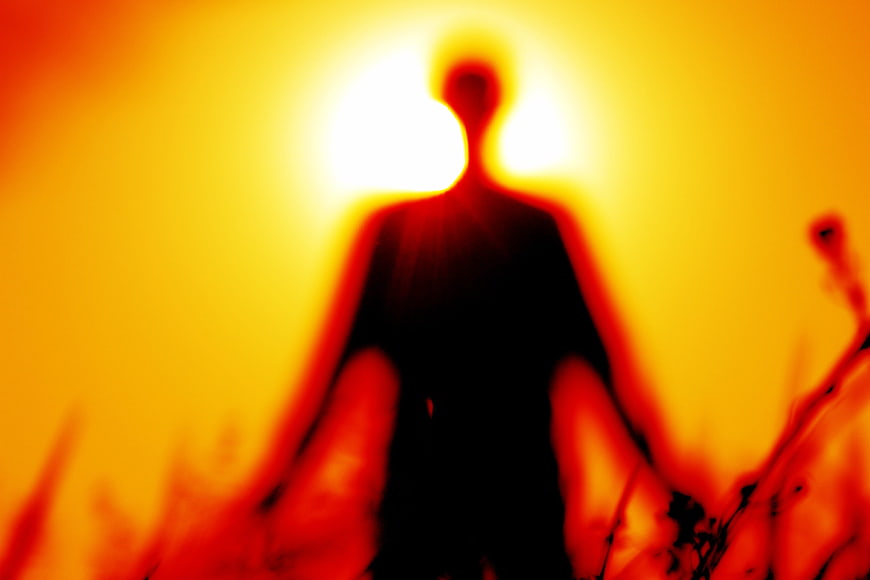 Blurred Silhouette of Person Meditating in Golden Light