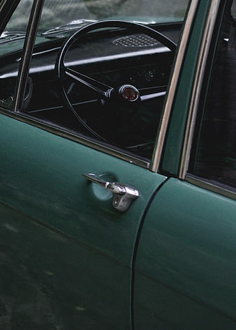 Close-up of vintage green car door and steering wheel