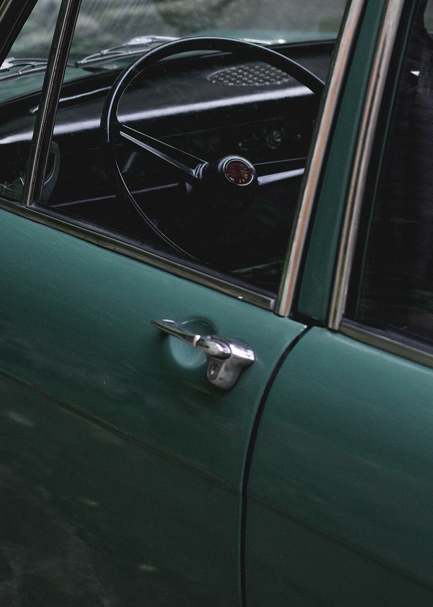 Close-up of vintage green car door and steering wheel