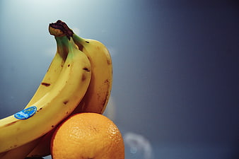 Close-up of yellow bananas and orange on blue background