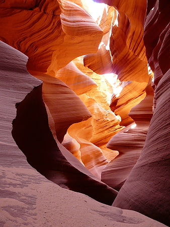 Sunlight streaming through swirling red sandstone canyon walls