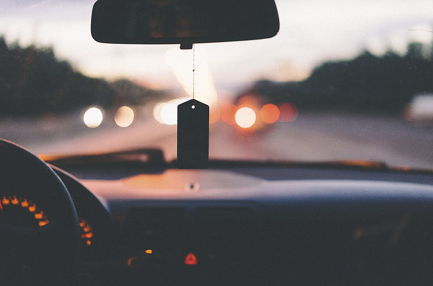 Car Air Freshener Hanging from Rearview Mirror at Dusk