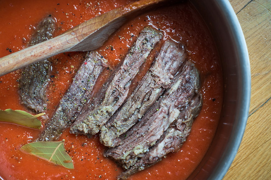 Sliced beef stew in tomato sauce with bay leaves