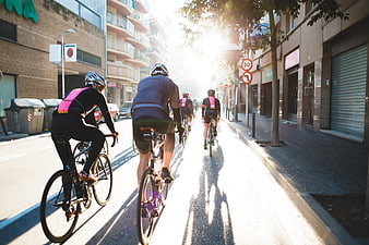 Group of cyclists riding down a sunlit city street