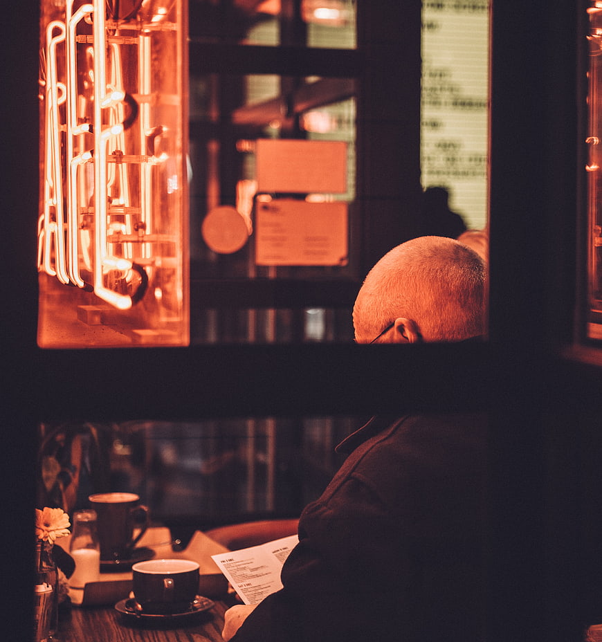 Senior man reading menu in warm cafe interior