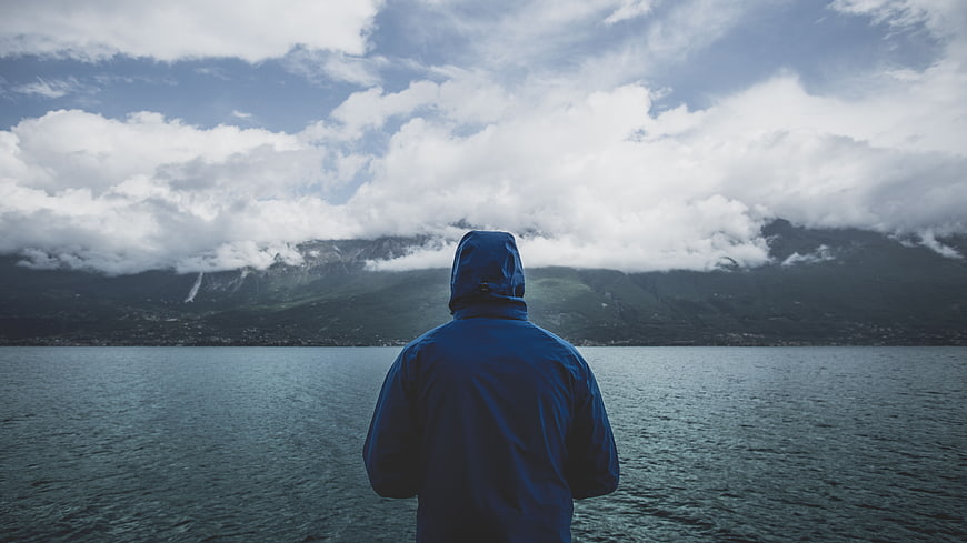 Man in Blue Hoodie Looking at Lake and Mountains