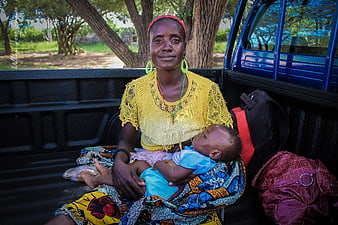 African mother and baby sitting in the back of a pickup truck