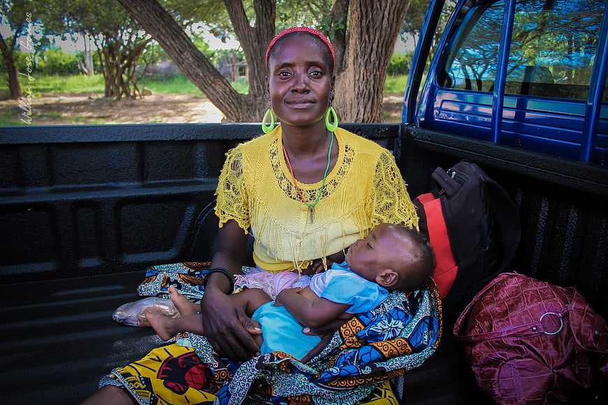 African mother and baby sitting in the back of a pickup truck