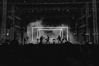 Silhouette of electronic music band performing on stage with neon lights