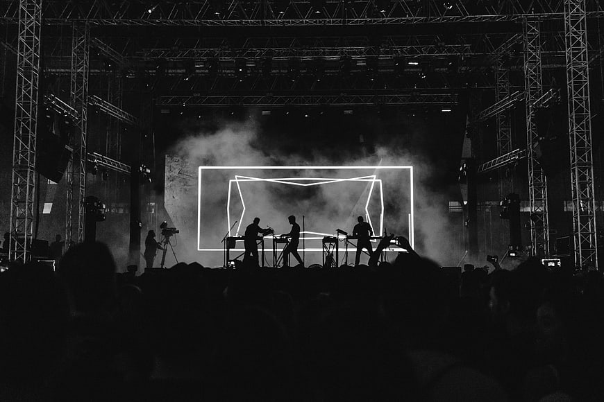 Silhouette of electronic music band performing on stage with neon lights
