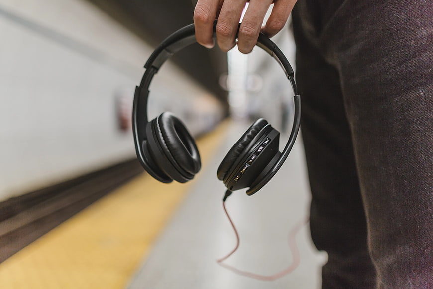Person Holding Black Headphones on Subway Platform