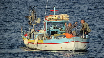 Two fishermen working on a traditional blue boat in the Mediterranean