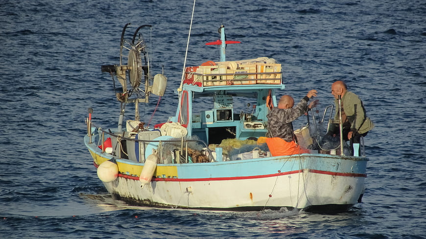 Two fishermen working on a traditional blue boat in the Mediterranean
