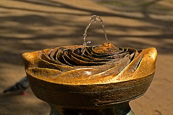 Close-up of bronze rose-shaped water fountain with flowing jet