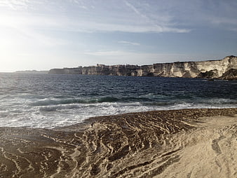 Sandy Beach with White Cliffs and Ocean Waves