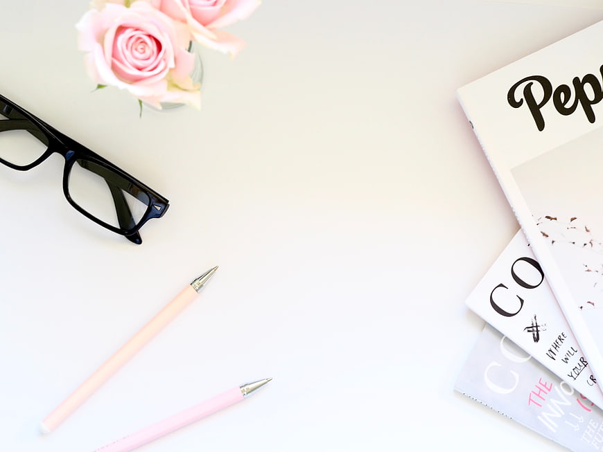 Minimalist flat lay with pink roses, glasses, and magazines