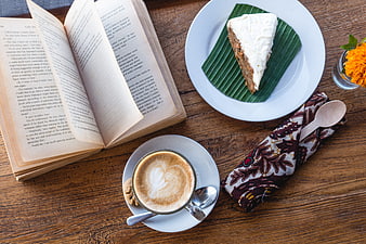 Top view of coffee, cake, and open book on wooden table