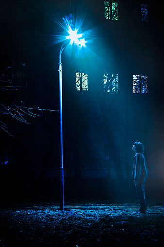 Man Standing Under Blue Street Light at Night