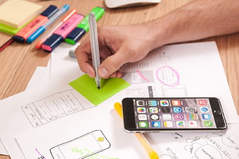 Hand writing on sticky note with smartphone and wireframes