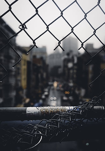 Rainy urban street view through chain link fence
