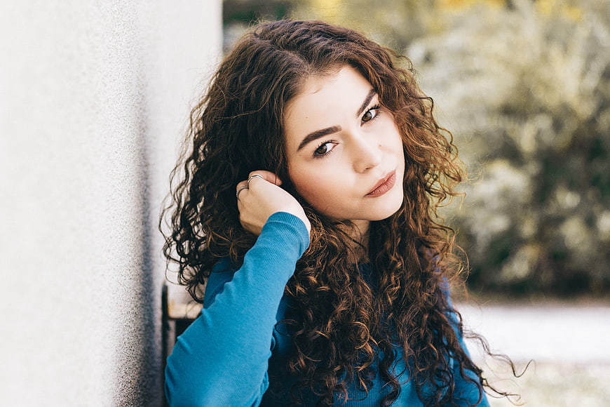 Portrait of Young Woman with Curly Hair in Blue Sweater
