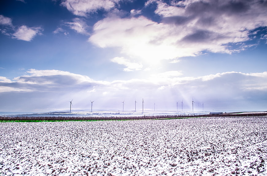 Snowy field with wind turbines and dramatic sky